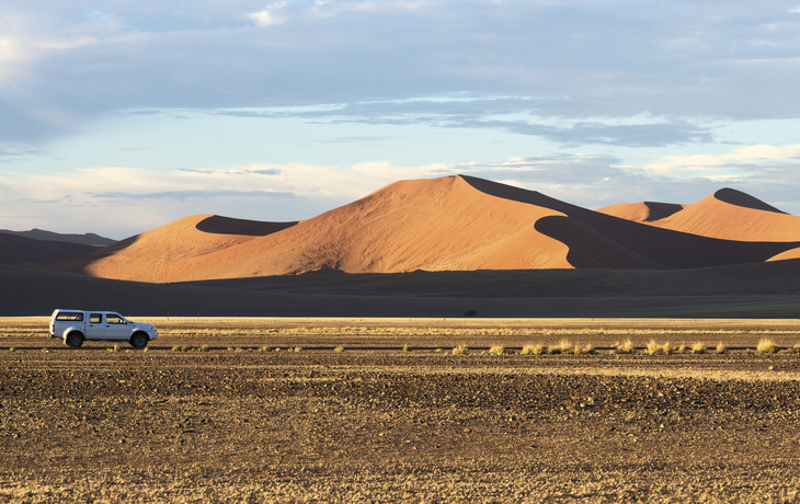 Geländewagen fährt durch die Namib Wüste