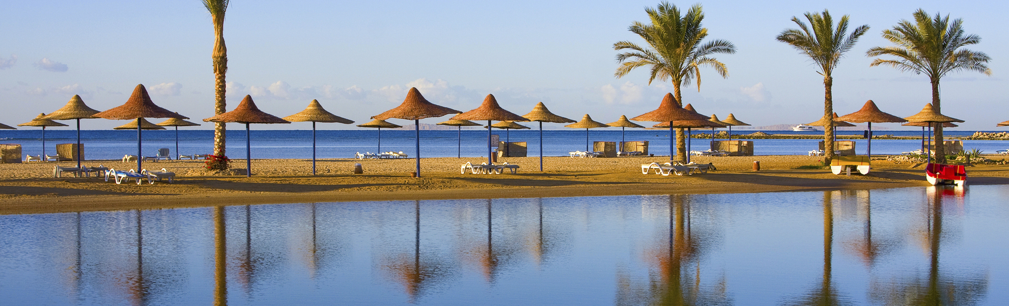 Strand mit Palmen und Strohschirmen in Ägypten