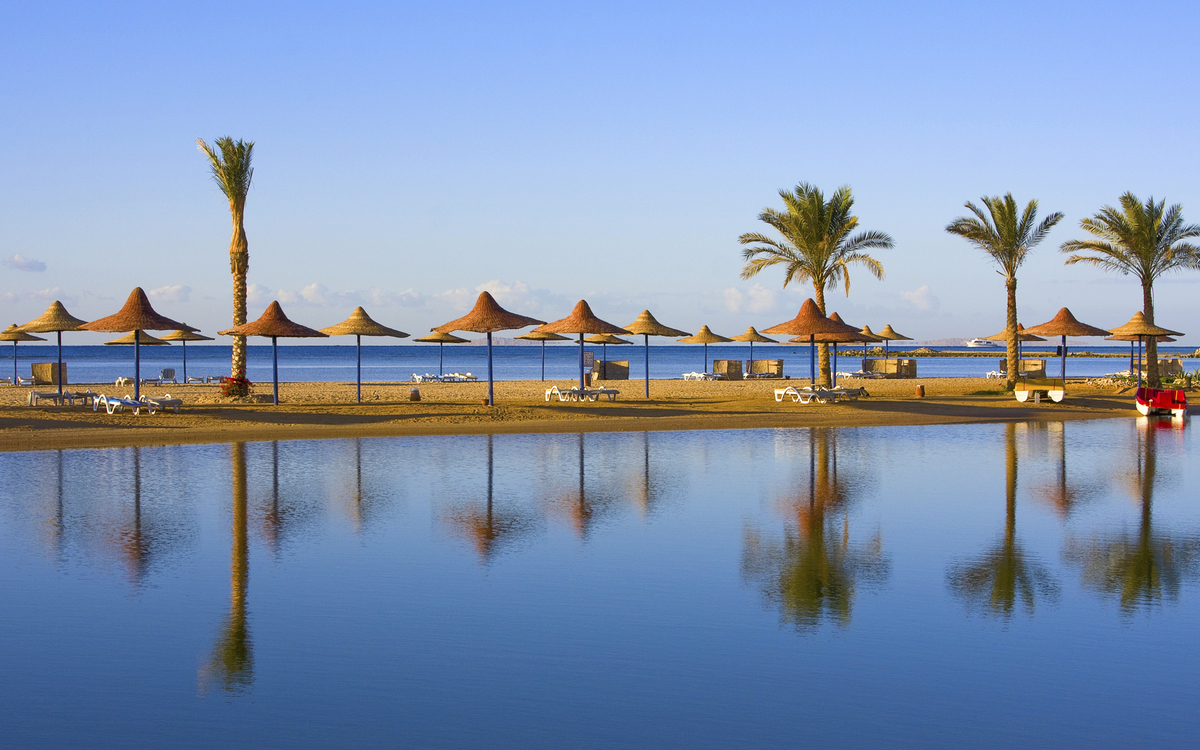 Strand mit Palmen und Strohschirmen in Ägypten
