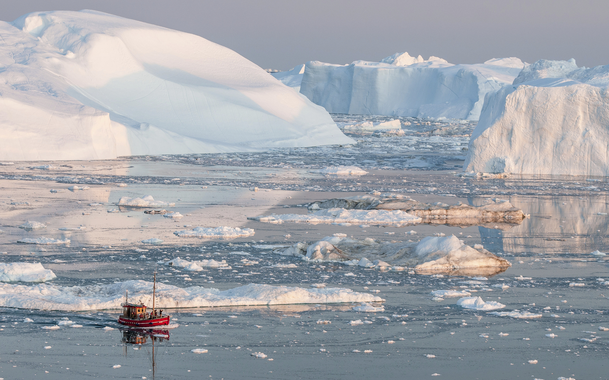 Kleines Fischerboot vor den Eisbergen in Groenland