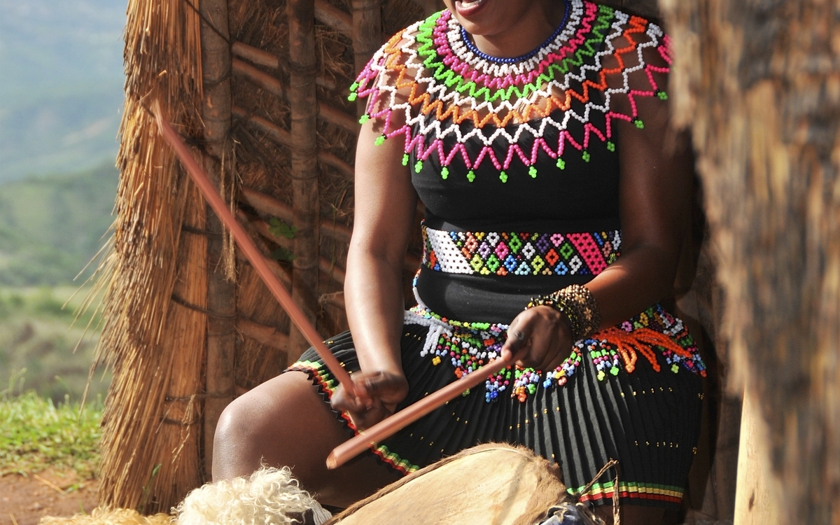 Südafrikanische, traditionell gekleidete Frau beim trommeln