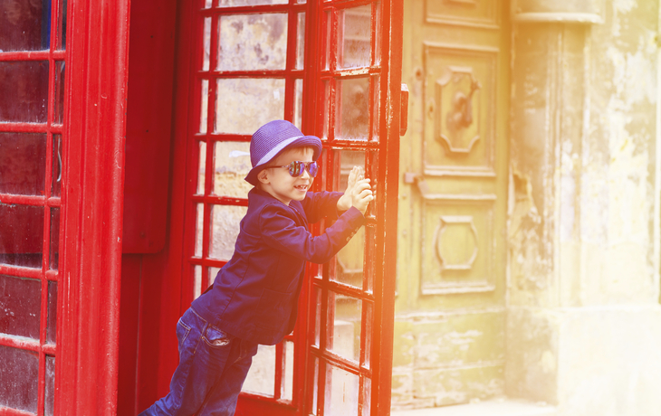 Junge in traditioneller Telefonzelle, England