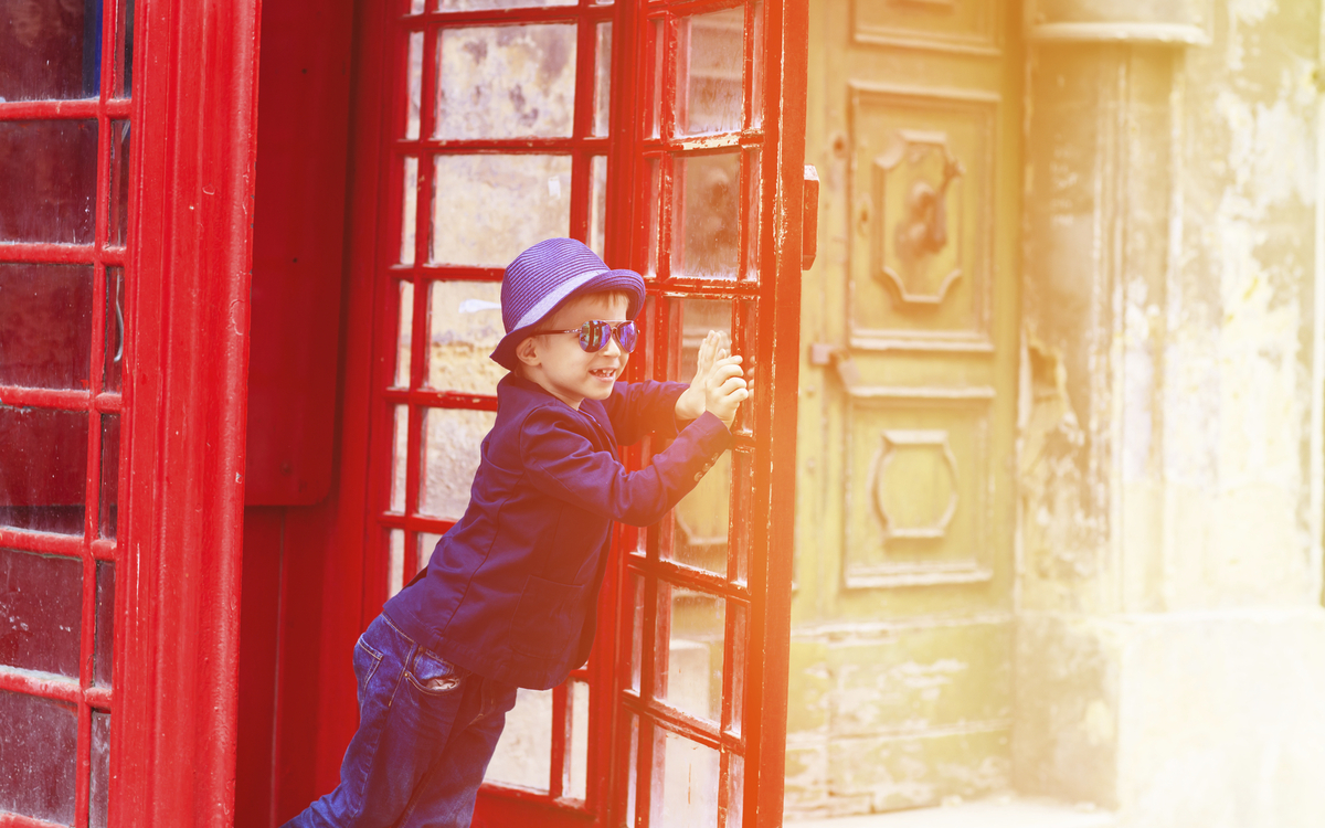 Junge in traditioneller Telefonzelle, England