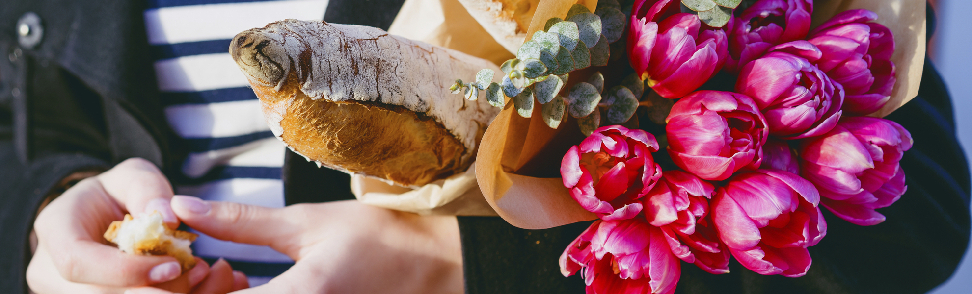 Frau mit Blumen und Baguette unterm Arm