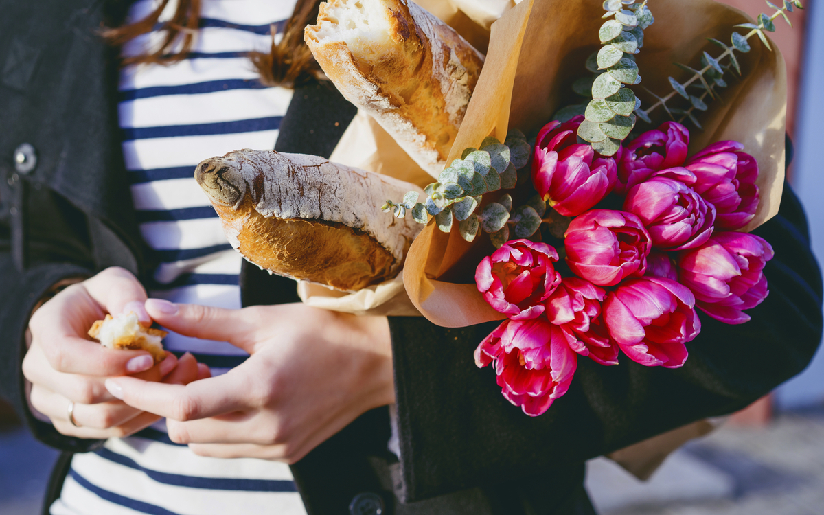 Frau mit Blumen und Baguette unterm Arm