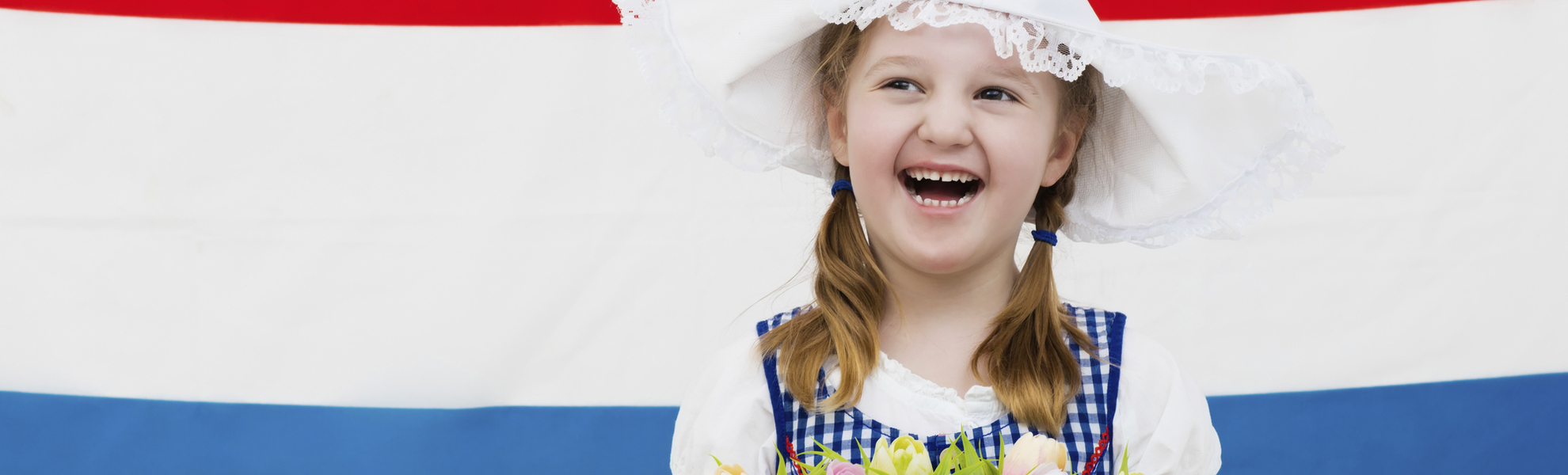 Mädchen in Tracht vor Landesfahne