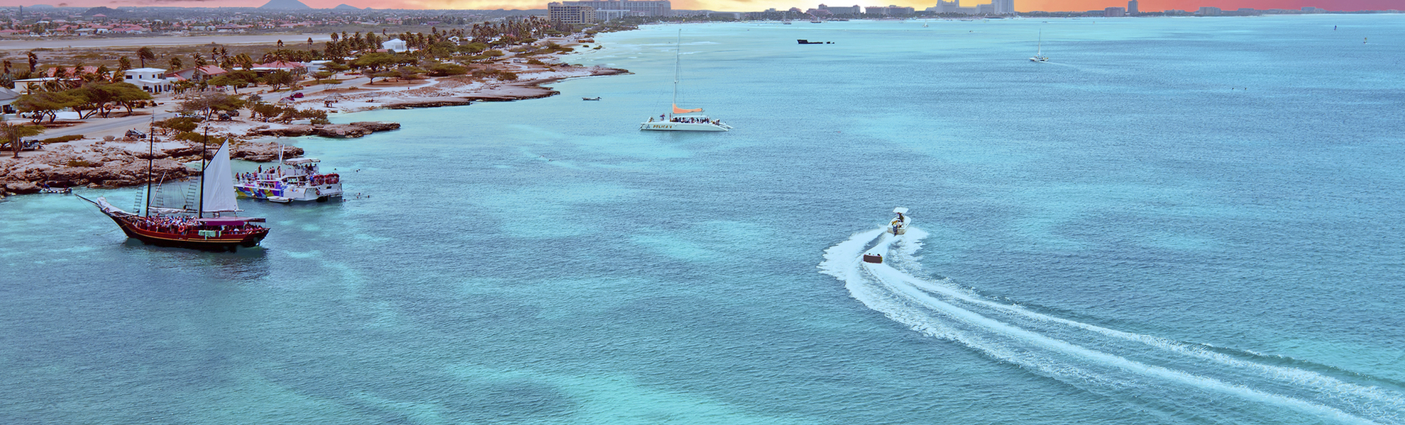 Sonnenuntergang über dem türkis-blauen Meer und dem Hafen von Aruba, Karibik