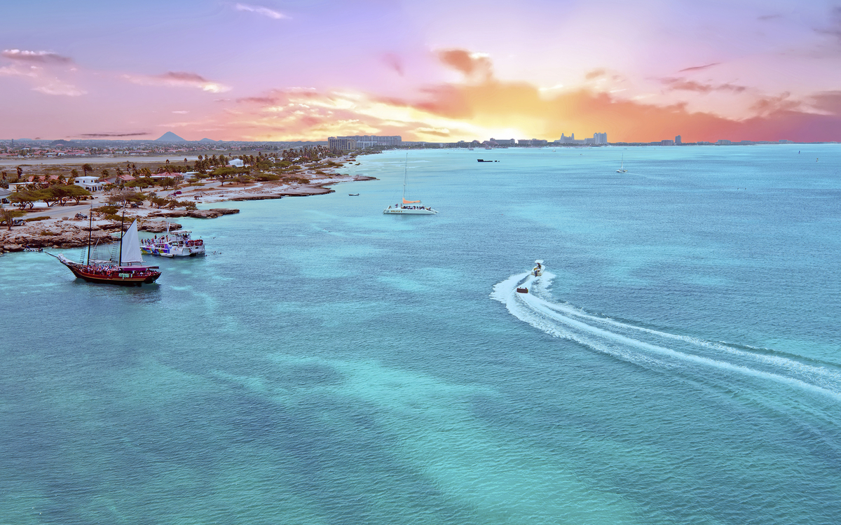 Sonnenuntergang über dem türkis-blauen Meer und dem Hafen von Aruba, Karibik