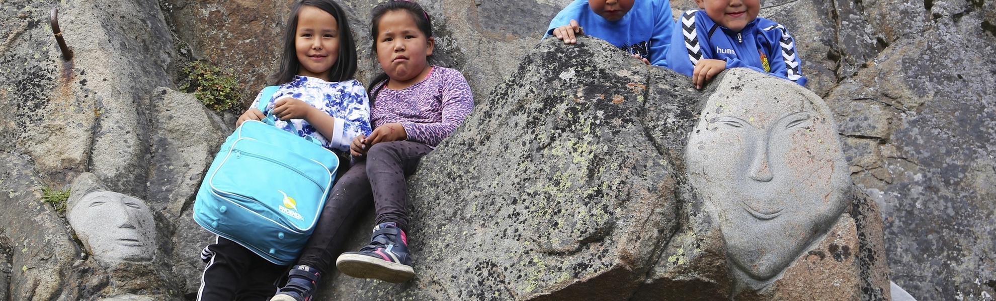 Kinder an steinernem Ornament in Qaqortoq, Grönland