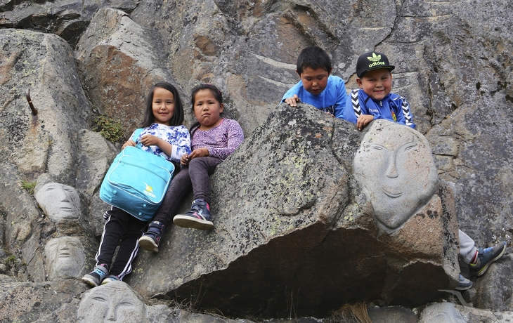 Kinder an steinernem Ornament in Qaqortoq, Grönland