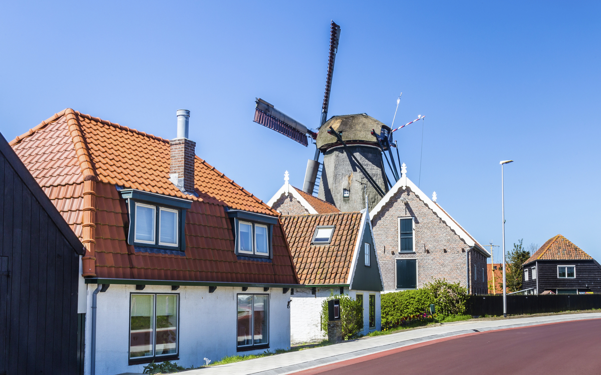 Häuserreihe vor einer Windmühle in Oudeschild, Niederlande
