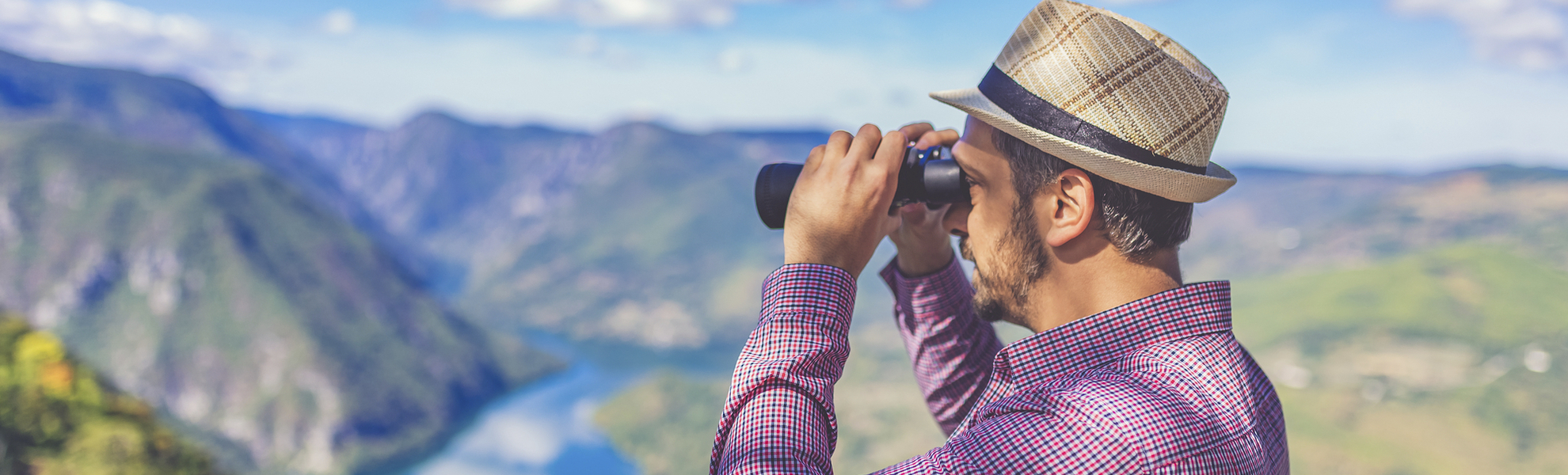Mann mit Fernglas blickt in einen Fjord