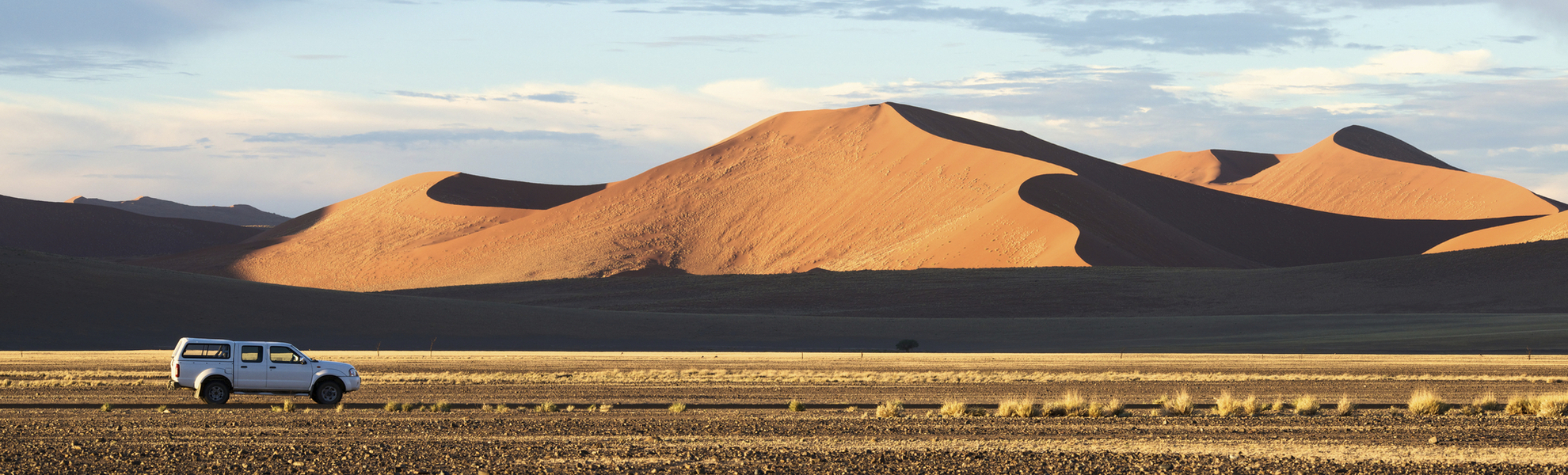 Geländewagen fährt durch die Namib Wüste