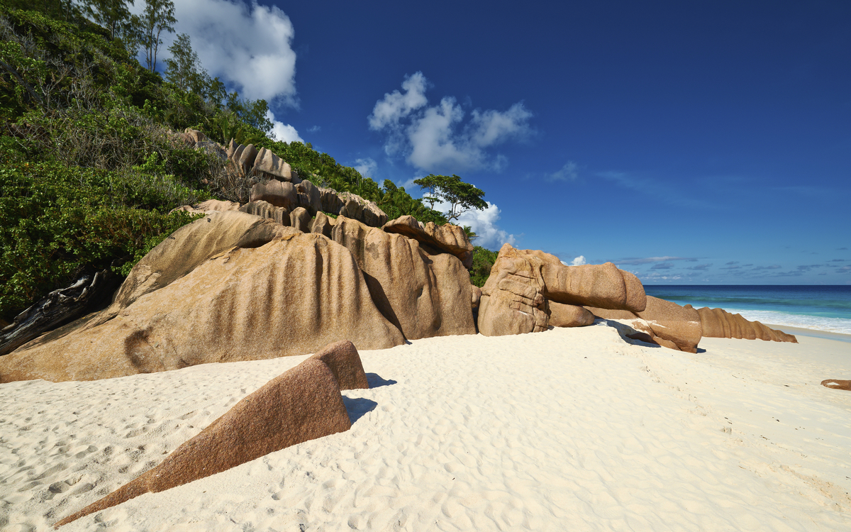 Feiner Sandstrand im Windschatten der Felsen auf La Digue, Seychellen
