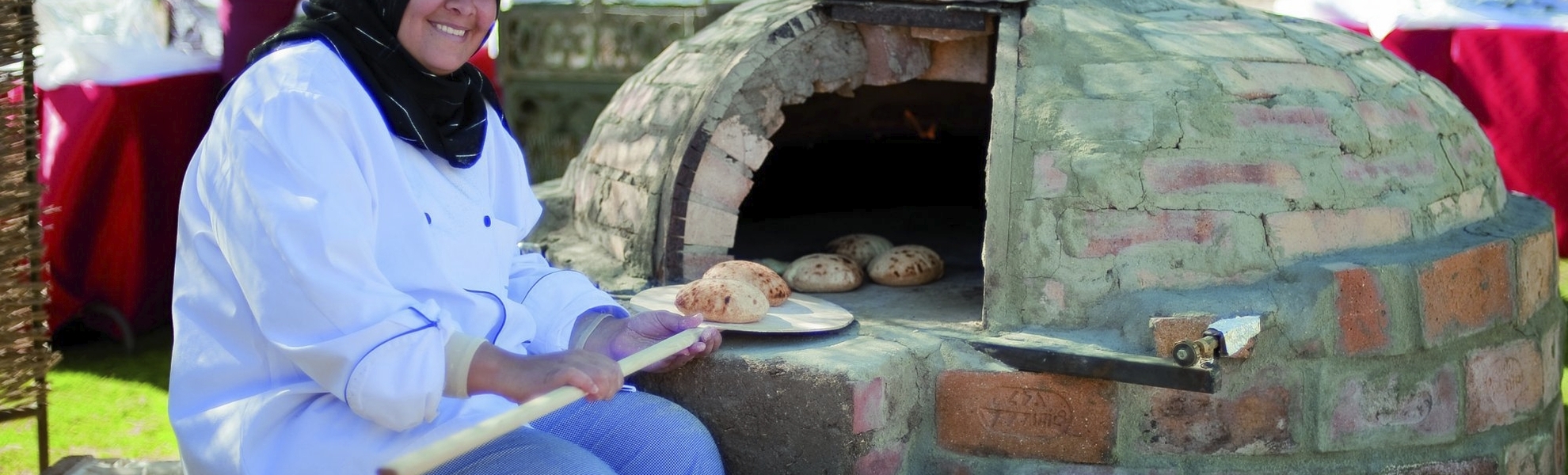 Bäckerin schiebt Brötchen in einen Steinofen auf einem Markt in Ägypten
