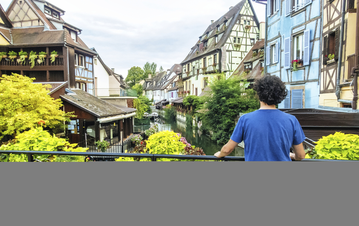 Mann am Brückengeländer eines Kanals in Colmar, Frankreich
