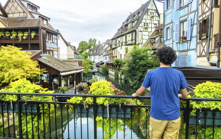 Mann am Brückengeländer eines Kanals in Colmar, Frankreich