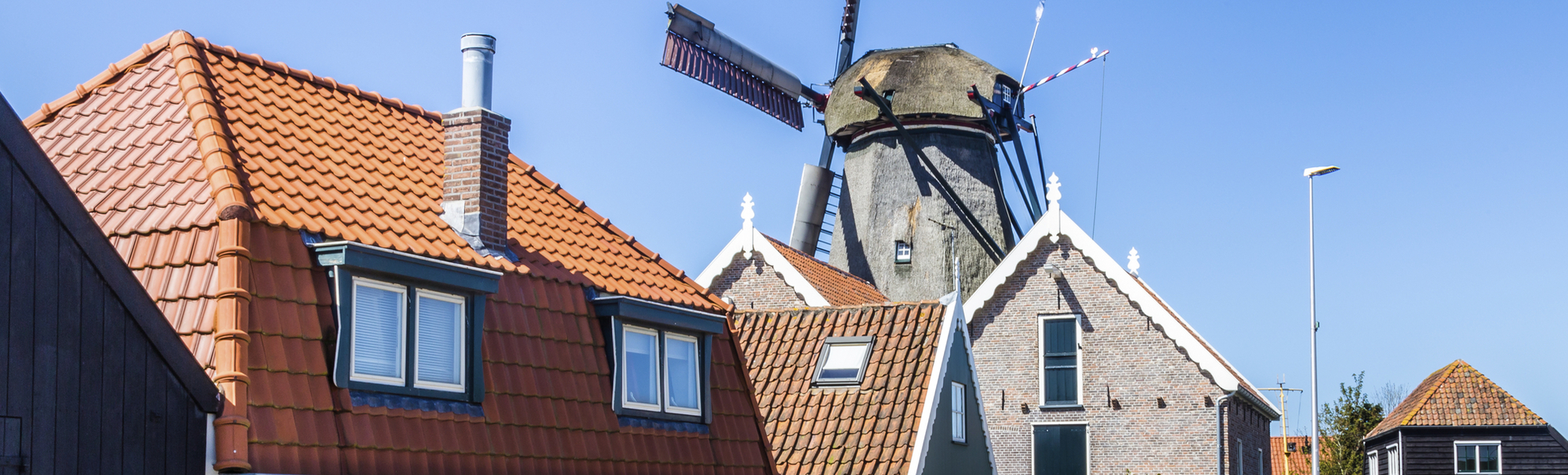 Häuserreihe vor einer Windmühle in Oudeschild, Niederlande