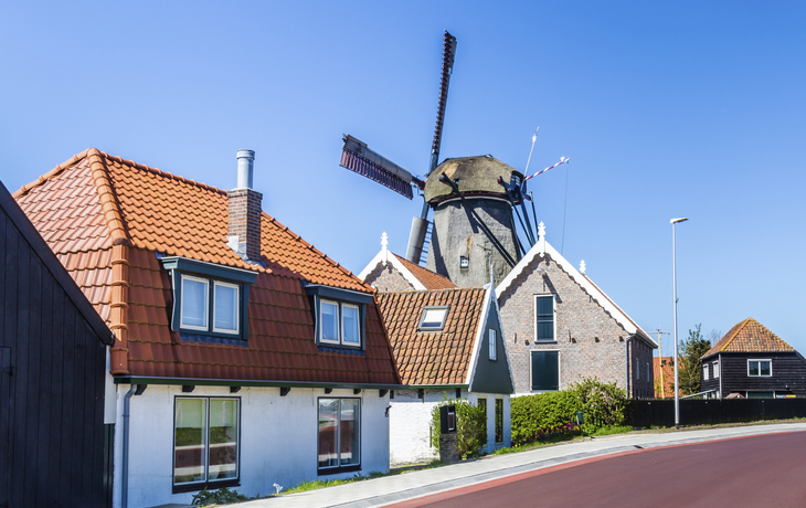 Häuserreihe vor einer Windmühle in Oudeschild, Niederlande