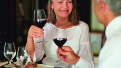 Lachendes Paar bei einem romantischen Abendessen mit Weingläsern.