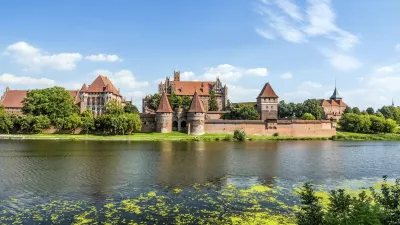 Die Marienburg, eine mittelalterliche Burg in Polen, erhebt sich majestätisch über dem Wasser.