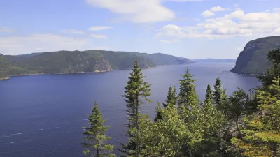 Weite Landschaft mit Fluss und Bergen im Hintergrund.