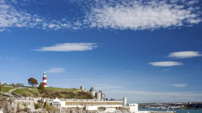 Roter und weißer Leuchtturm steht auf einer felsigen Klippe am Meer.