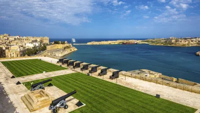 Historische Kanonen stehen auf einer grünen Rasenfläche mit Blick auf das blaue Meer.