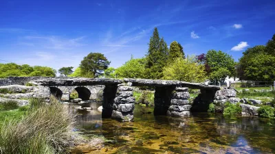 Historische Steinbrücke über einen klaren Fluss in Dartmoor