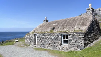 Traditionelles schottisches Steinhaus mit Strohdach an der Küste.
