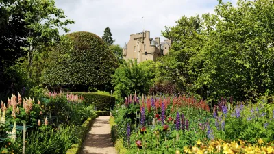 Blühender Schlossgarten mit Kiesweg und bunten Blumenbeeten.