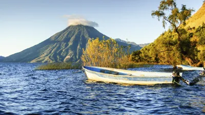 Ein buntes Boot fährt auf dem Atitlán-See mit Vulkan im Hintergrund