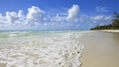 Türkisblaues Karibisches Meer trifft auf weißen Sandstrand.