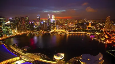 Singapurs Skyline bei Nacht mit leuchtenden Gebäuden und Wasser.