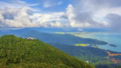 Grüne Berghänge mit Blick auf das türkisfarbene Meer und den Himmel.