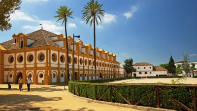 Historische Reitschule mit gelber Fassade und Palmen in Jerez, Spanien.