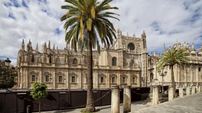 Die Kathedrale von Sevilla mit Palmen im Vordergrund.