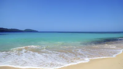 Türkisblaues Karibisches Meer trifft auf goldenen Sandstrand.