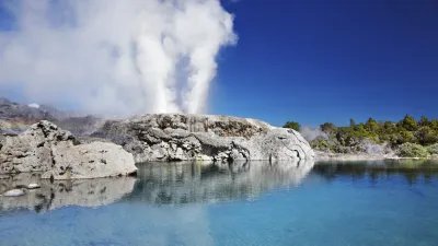 Heißer Geysir spuckt Wasser in die Luft über türkisfarbenem Becken