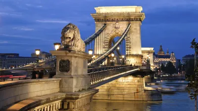 Die Kettenbrücke in Budapest bei Nacht mit dem Burgpalast im Hintergrund.
