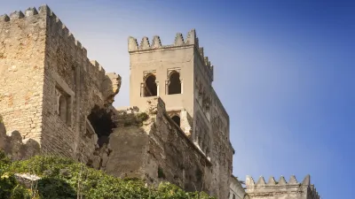 Historische Festungsmauern ragen über grüner Vegetation empor.