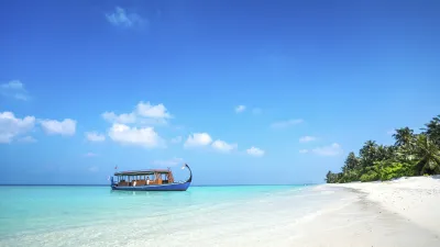 Türkisblaues Wasser umspült einen Strand mit einem kleinen Boot