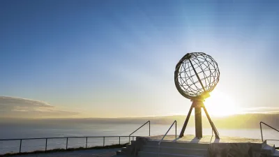 Nordkap-Monument bei Sonnenaufgang mit Blick auf das Meer