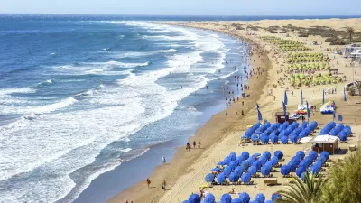 Sonnenbädernde Menschen und Wellen am Strand von Playa de Ingles