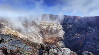 Kraterlandschaft mit Felsbrocken und Dampf in Reunion