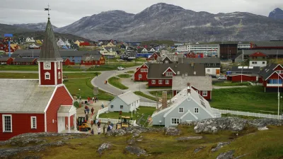 Rote und weiße Häuser prägen das grönländische Stadtbild mit Blick auf die Berge.