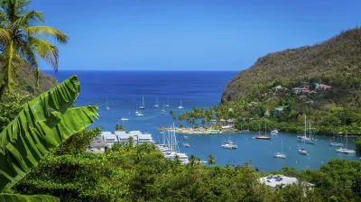 Karibische Bucht mit Segelbooten und grüner Vegetation.