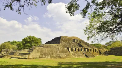 Ein weißes Schiff fährt auf einem Fluss an Gebäuden vorbei.