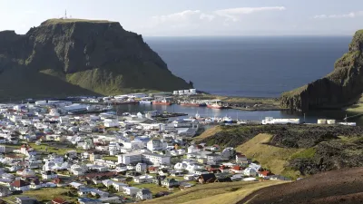 Bunte Häuser und Boote liegen an der Küste der isländischen Insel Heimaey.