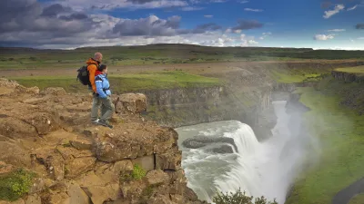 Zwei Wanderer blicken auf den beeindruckenden Gullfoss Wasserfall in Island.